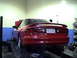 1997 Ford Probe - A red coupe is positioned on a lift in a garage, showing its rear end and a custom license plate.