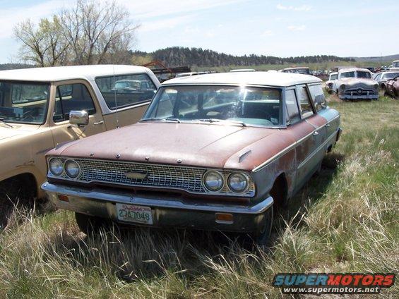 Front view of a rusty 1963 Ford station wagon with a chrome grille and a California license plate