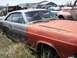 1968 Ford Coupe - This weathered coupe sits in a junkyard, surrounded by other vehicles under a partly cloudy sky.