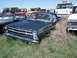 1968 Ford Coupe - A dark blue pickup truck sits in a junkyard surrounded by overgrown weeds and other vehicles.