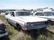 1968 Ford Coupe - A white 1968 Ford Coupe with red racing stripes sits in a junkyard, surrounded by other vehicles.