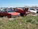 1968 Ford Coupe - Two red Ford coupes from 1968 sit in a junkyard under a clear blue sky.