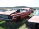 1968 Ford Coupe - This red coupe sits in a junkyard, showing signs of significant wear and damage, including a broken windshield and missing parts.