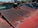 1968 Ford Coupe - A heavily rusted 1968 Ford Coupe sits in a junkyard, its hood showing signs of decay and damage.
