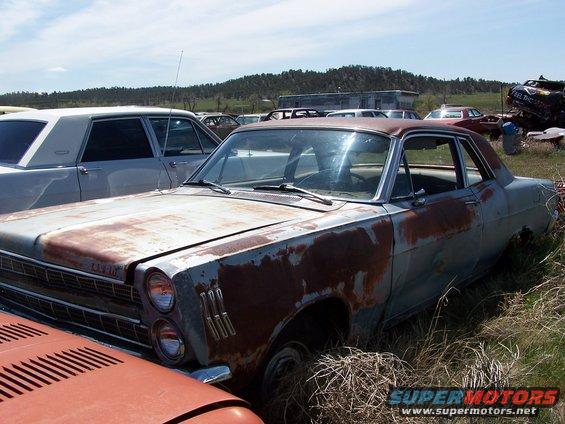 Rusty 1966 Ford Fairlane coupe in a junkyard, 3q front view
