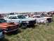 1968 Ford Coupe - A collection of vintage cars sits in a grassy junkyard under a clear blue sky.