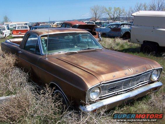 Brown 1968 Ford Ranchero in a junkyard, front 3/4 view, showing rust and overgrown grass