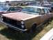 1968 Ford Coupe - This weathered sedan, likely a 1967 model, sits among other vehicles in a junkyard, showing significant rust and missing its grille.