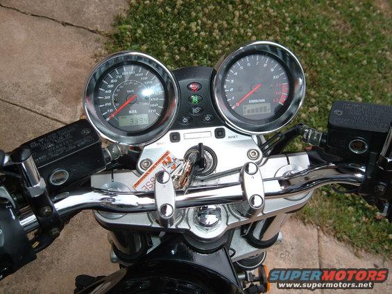 Motorcycle dashboard with two analog gauges, keys in ignition, and chrome handlebars