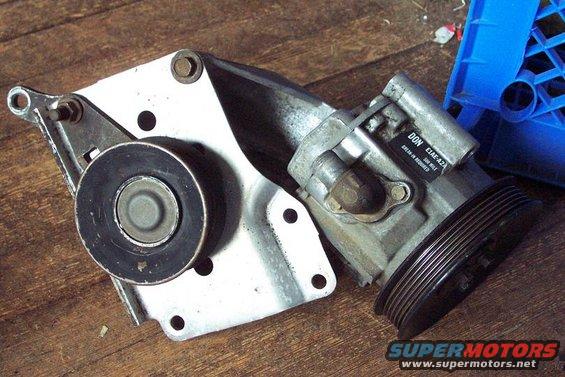 Power steering pump assembly with pulley and mounting bracket on a wooden surface
