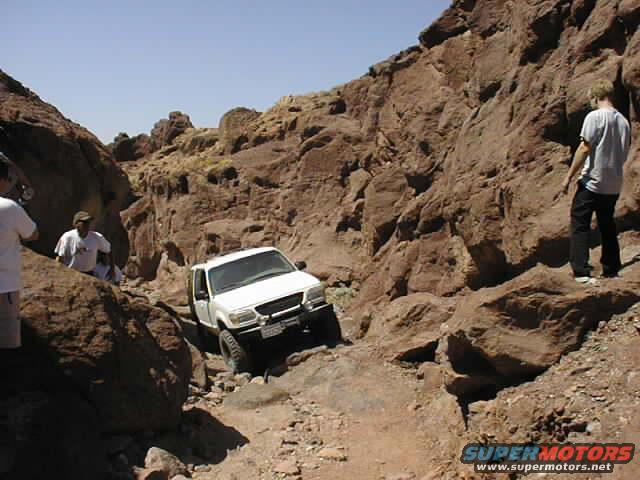 1997 Ford Ranger navigating a rocky trail with two people watching