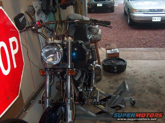 Motorcycle front end in garage with stop sign and two cars in background