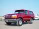 1995 Ford Bronco - This red 1995 Ford Bronco is parked near a dock with a boat visible behind it.