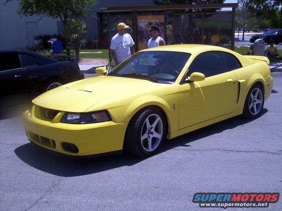 Yellow 2002 Ford Mustang parked next to a black car