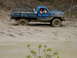 1979 Ford Bronco - This truck is deep in the mud, with its tires submerged and struggling to gain traction.