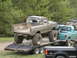 1979 Ford Bronco - A heavily mud-covered pickup truck is being transported on a trailer, with other vehicles visible in the background.