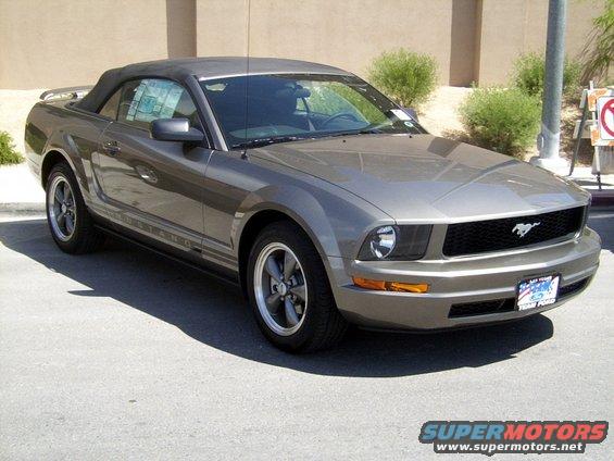 Gray convertible Mustang with black top, side stripe, and aftermarket wheels