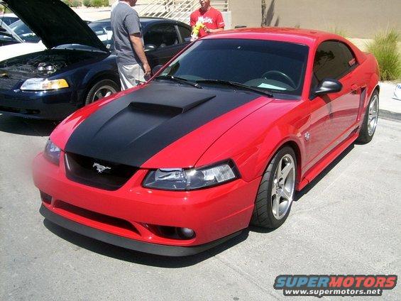 Red Mustang with black hood scoop and stripe, parked next to a dark blue car with its hood up