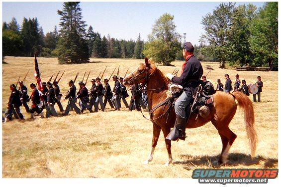 Cavalry officer on horseback watches marching Union soldiers and drummer boy