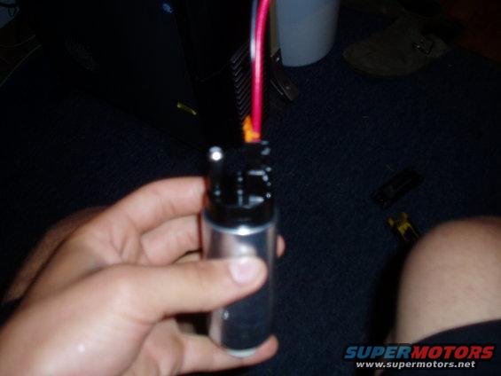 Hand holding a silver and black fuel pump with red and black wires