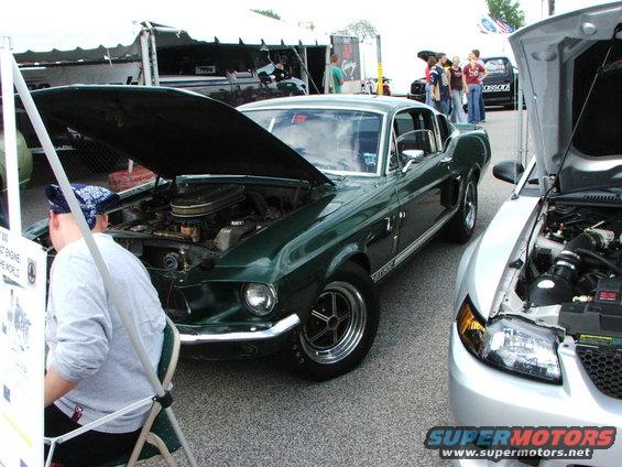 Green 1967 Mustang fastback with hood open, parked next to a silver car