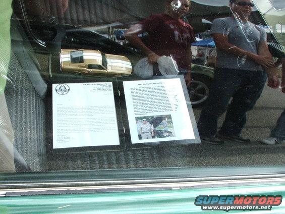 Gold 1971 Ford Mustang model with white stripes on display behind glass