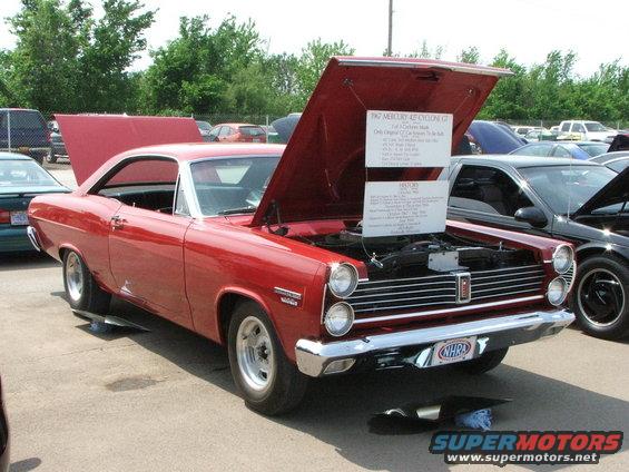 Red 1967 Mercury Cyclone GT coupe with hood open, showing engine and display signs