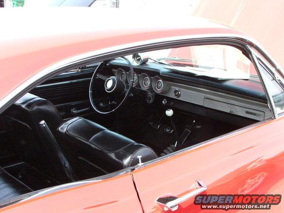 Interior view of a vintage car, showing black seats, dashboard with gauges, and a floor shifter. A 'Comet GT' badge is visible on the dashboard