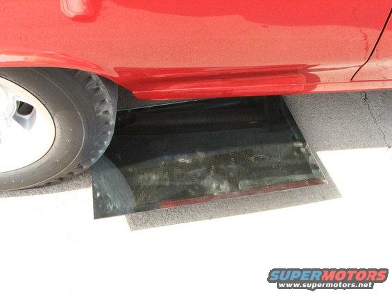 Red car side panel with a broken window piece on the ground