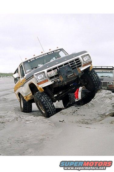 Ford Bronco climbing a sand dune, another Bronco behind it. Text on windshield says '2 BIG BRONCOS 4X4 CLUB'