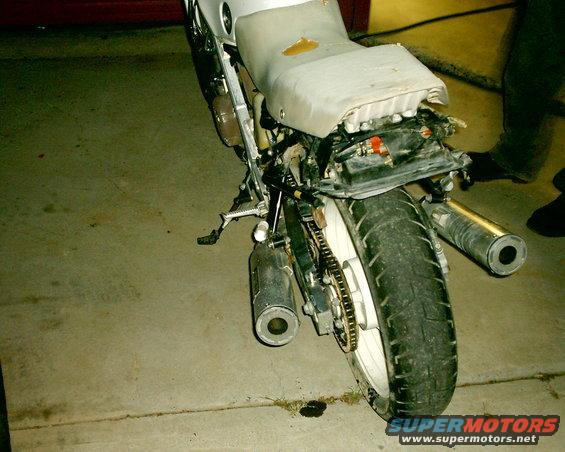 Motorcycle rear end with dual exhaust pipes and a worn seat