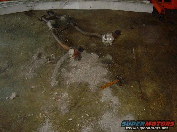 Exhaust system parts on concrete floor with hammer