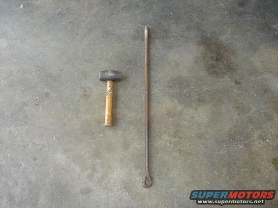 Hammer and a long metal rod with a loop on the end, lying on a concrete floor