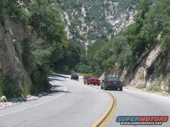Three cars on a winding mountain road, rear view