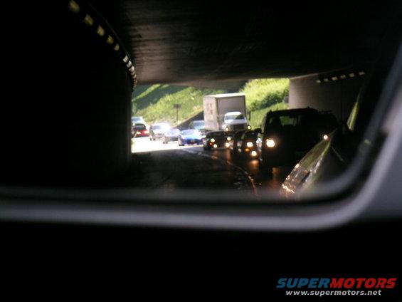 Traffic jam viewed in side mirror, with a truck and several cars visible