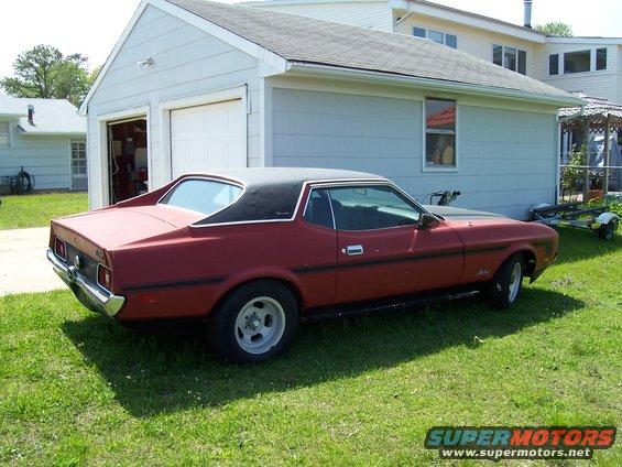 Red 1971 Ford Mustang coupe with a black vinyl top parked on grass