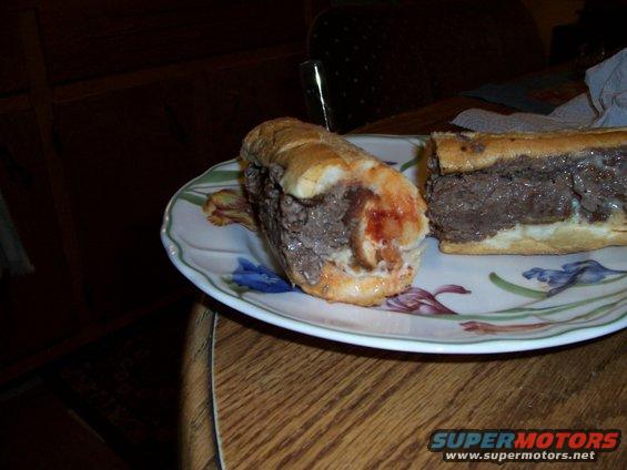 Two steak sandwiches on a plate with a Supermotors.net watermark
