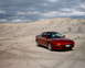 1996 Ford Probe - A red 1996 Ford Probe sits in a dry, dusty landscape under a cloudy sky.