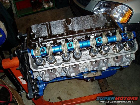 V8 engine on an orange stand, with blue valve covers and intake manifold