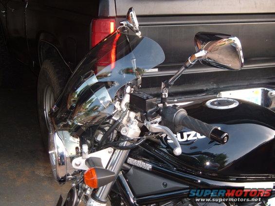 Suzuki motorcycle's front end with a black windshield and chrome accents. A black truck is behind it