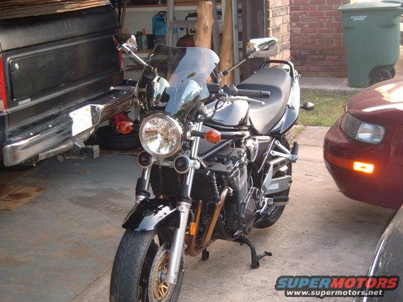 Black motorcycle parked in a garage next to a black truck and a red car