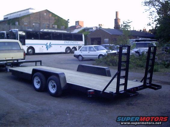 Flatbed trailer parked in front of a building with a bus and cars behind it