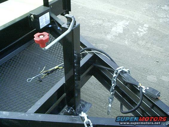 Trailer tongue with a red winch handle, safety chains, and a wiring harness