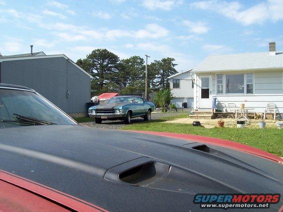 Teal 1970 Chevrolet Chevelle parked in a driveway with a red car hood in the foreground