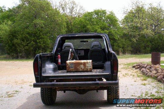 Black Ford Bronco with aftermarket bumper and spare tire carrier, seen from the rear