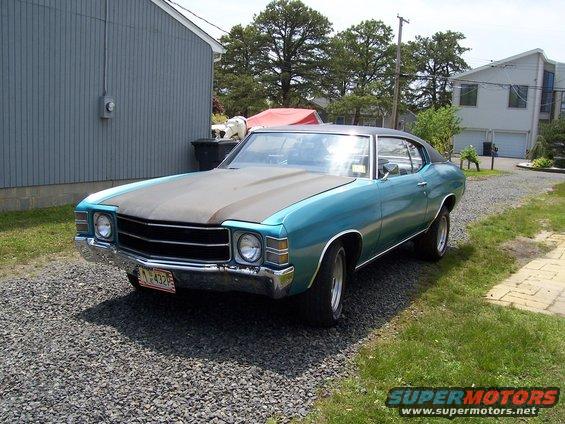1971 Chevrolet Chevelle coupe with a dark hood and teal body, parked on a gravel driveway