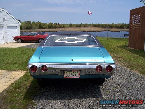 Rear view of blue 1971 Chevrolet Chevelle with black vinyl top, parked next to a red Ford Mustang