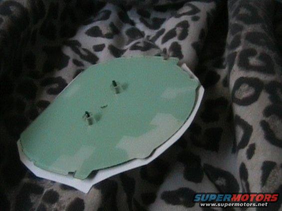 Green dashboard component with two protruding pins, on a leopard-print fabric
