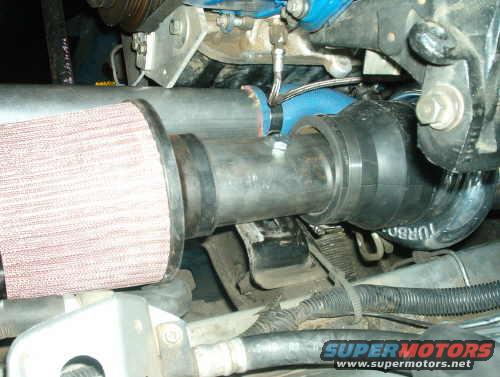 Engine bay showing a red air filter connected to a metal pipe, with black turbo piping visible