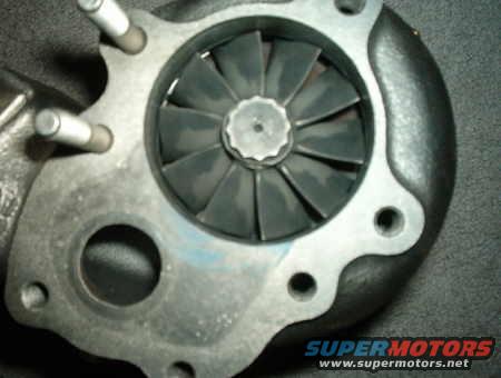 Turbocharger turbine wheel with black blades and silver center nut. Supermotors.net logo visible